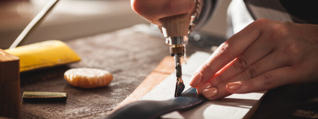 職人が、細工された革に刃物を入れている手作業の様子